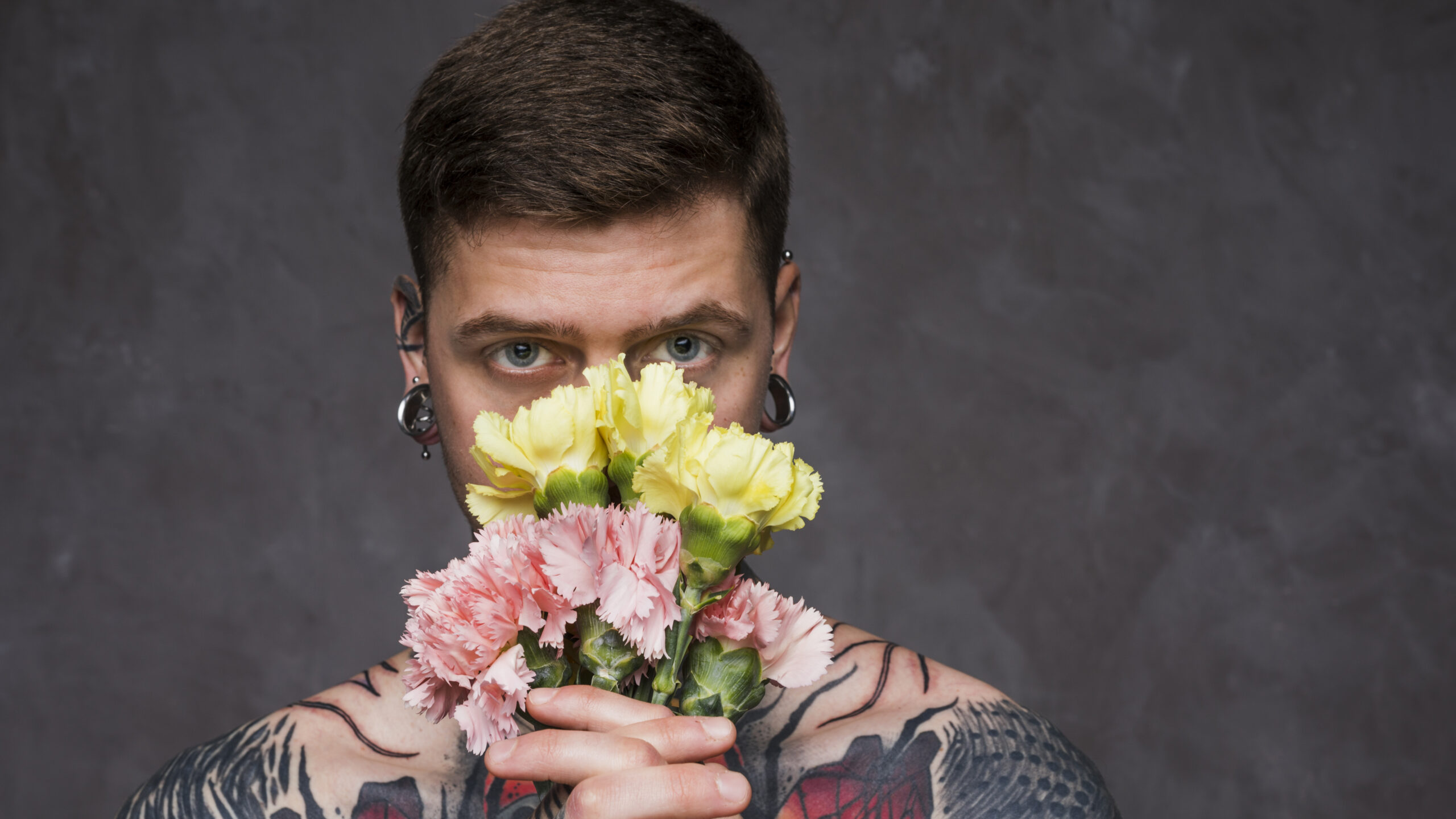 close-up-tattoo-young-man-with-pierced-ears-holding-pink-yellow-carnation-flowers-front-his-mouth-scaled Últimas postagens